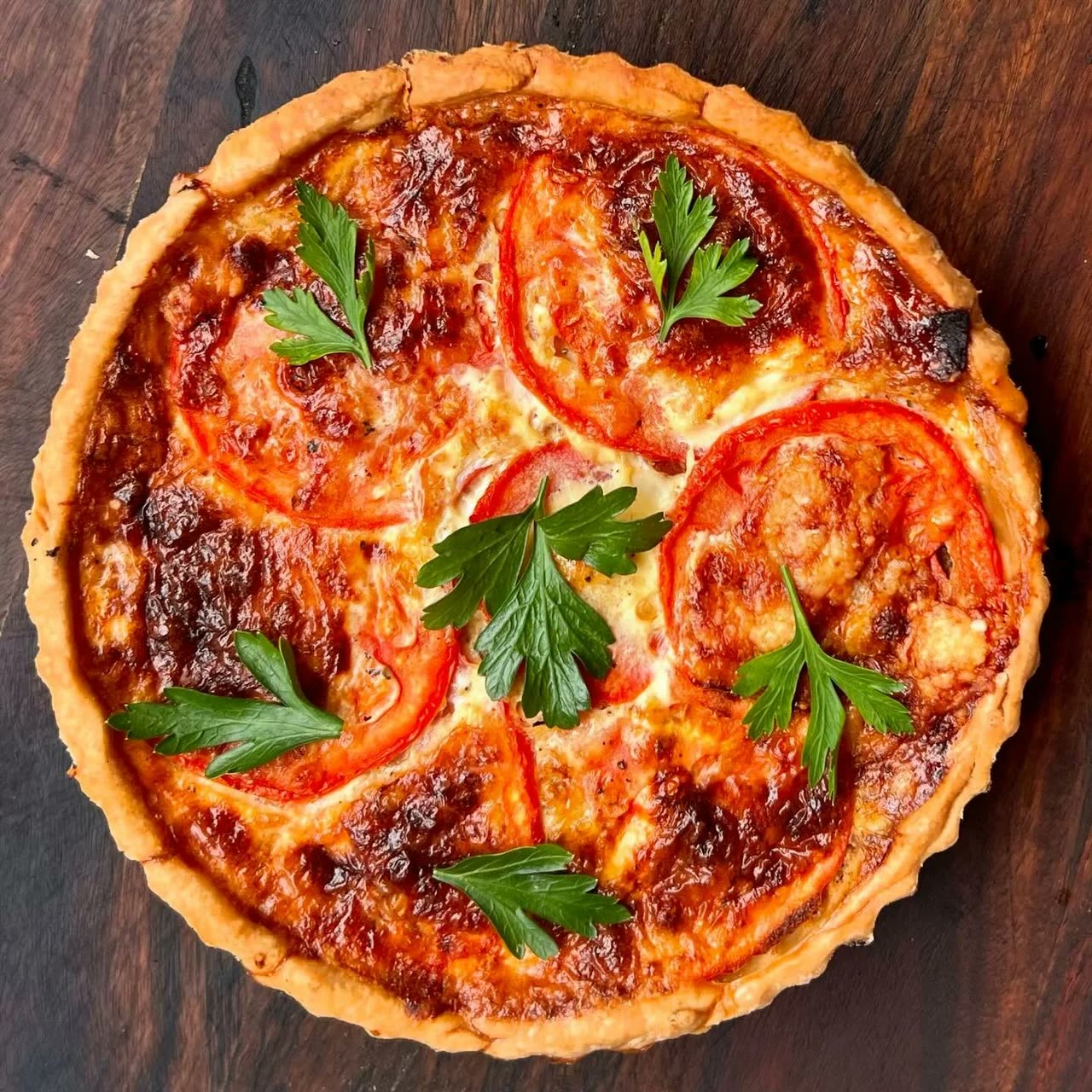 A whole quiche Lorraine topped with tomato and parsley