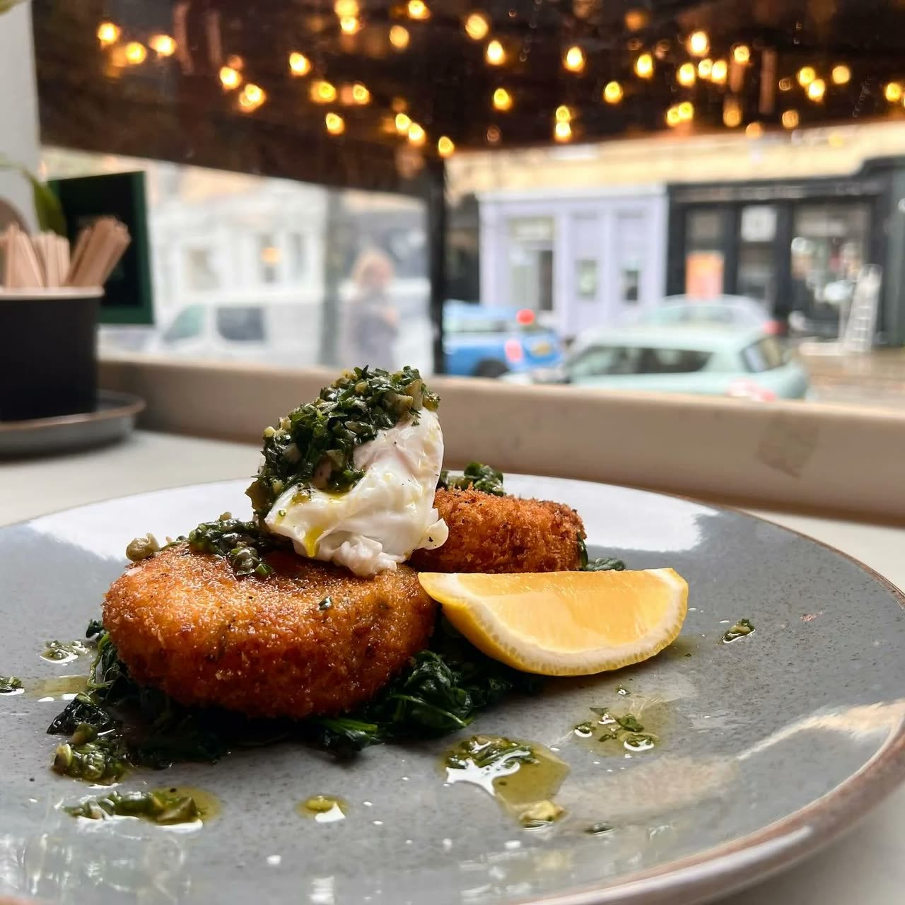 Hake fish cakes on buttered spinach with a poached egg and salsa verde