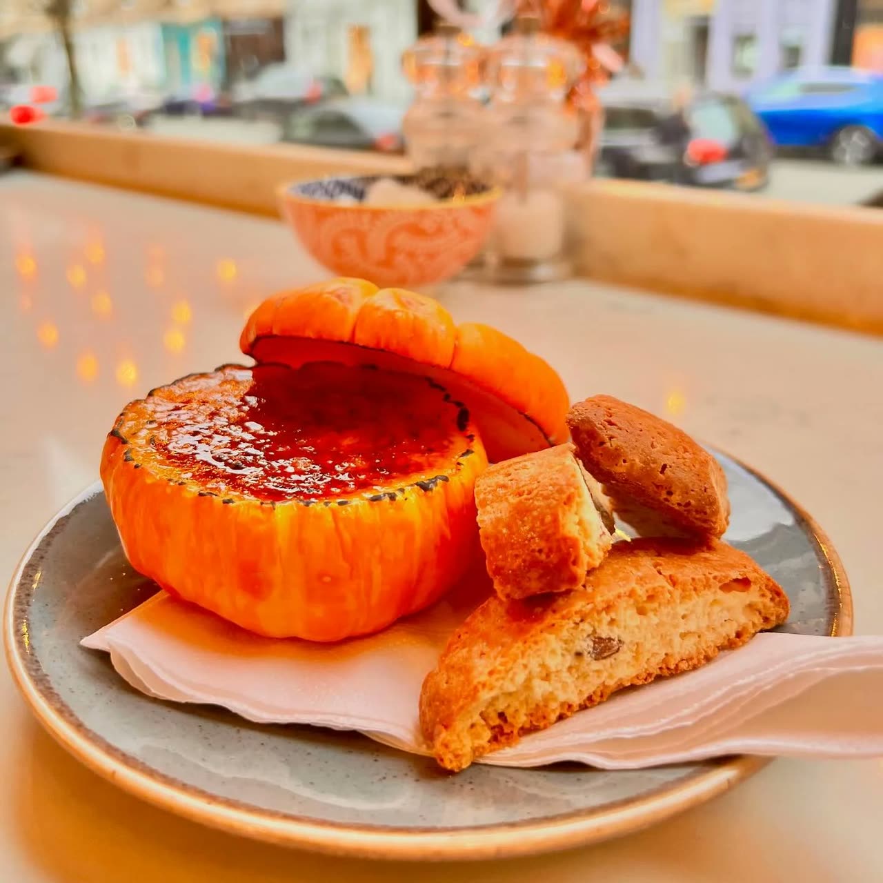 A pumpkin cr&egrave;me br&ucirc;l&eacute;e served in a small pumpkin with biscotti