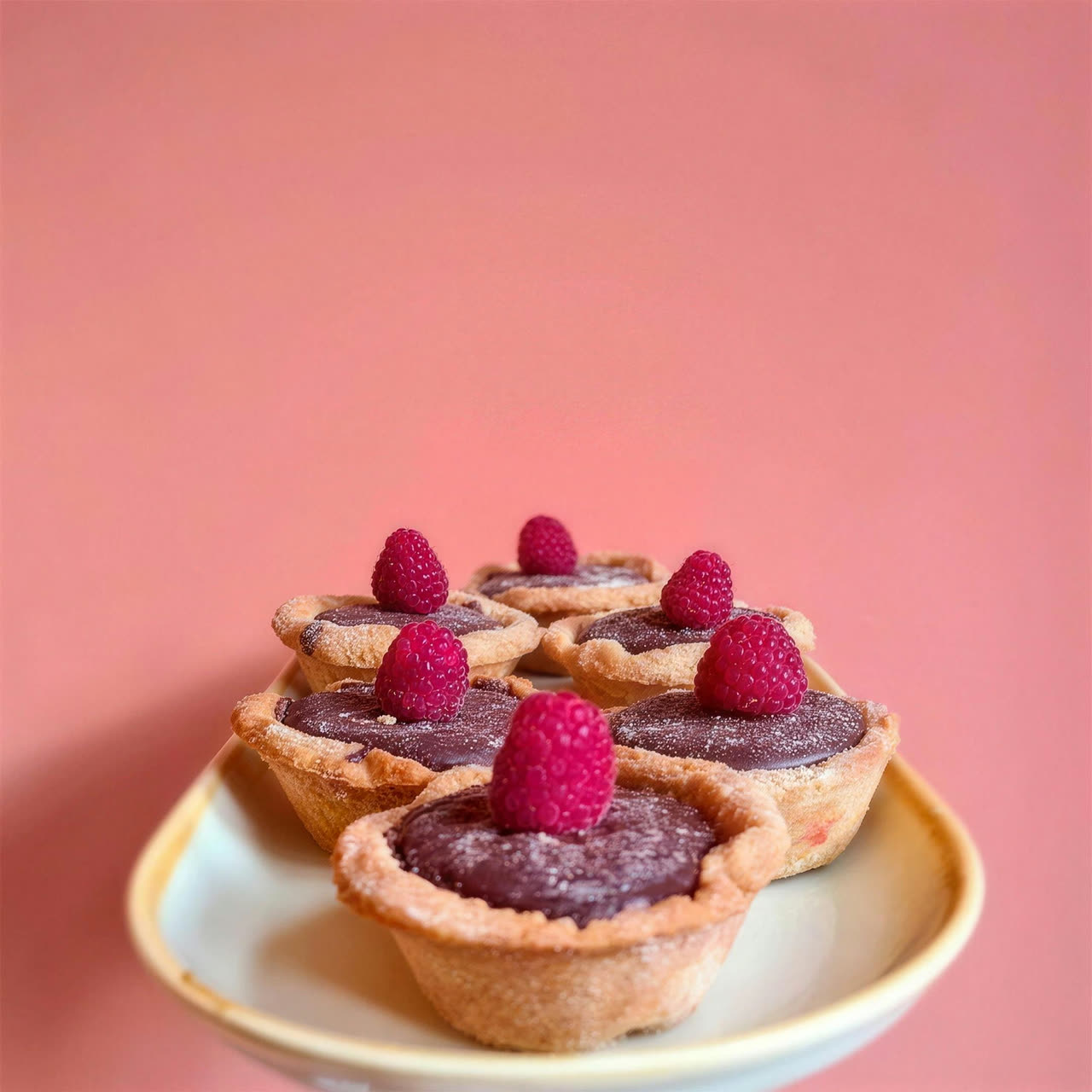 Raspberry and frangipane tarts on a cake stand