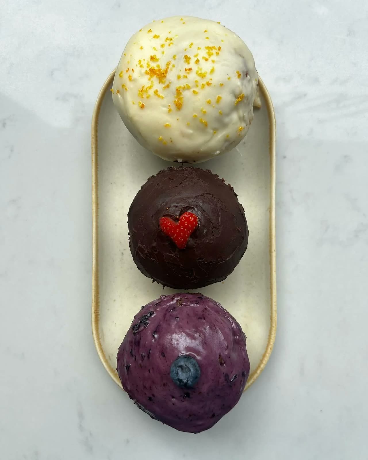 Three iced homemade muffins on a gold tray